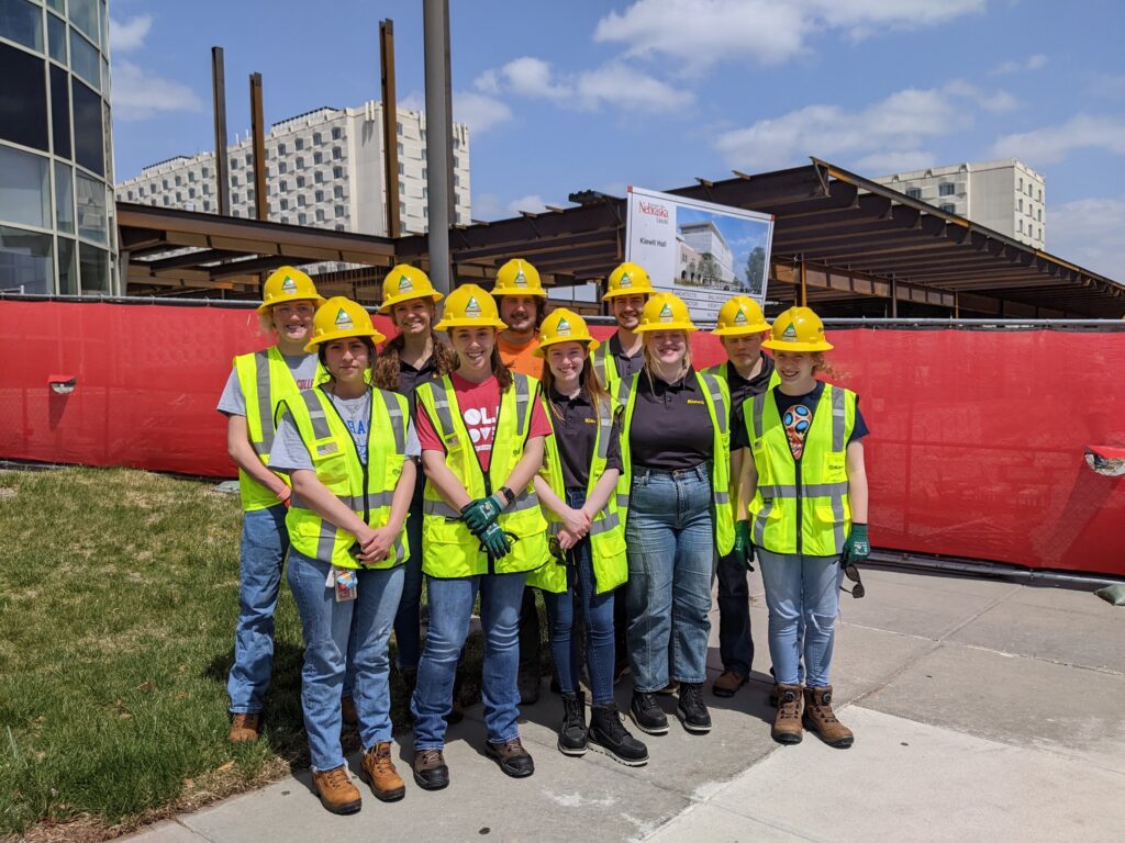 Group of students in yellow construction vests standing in front of the future Kiewit Hall