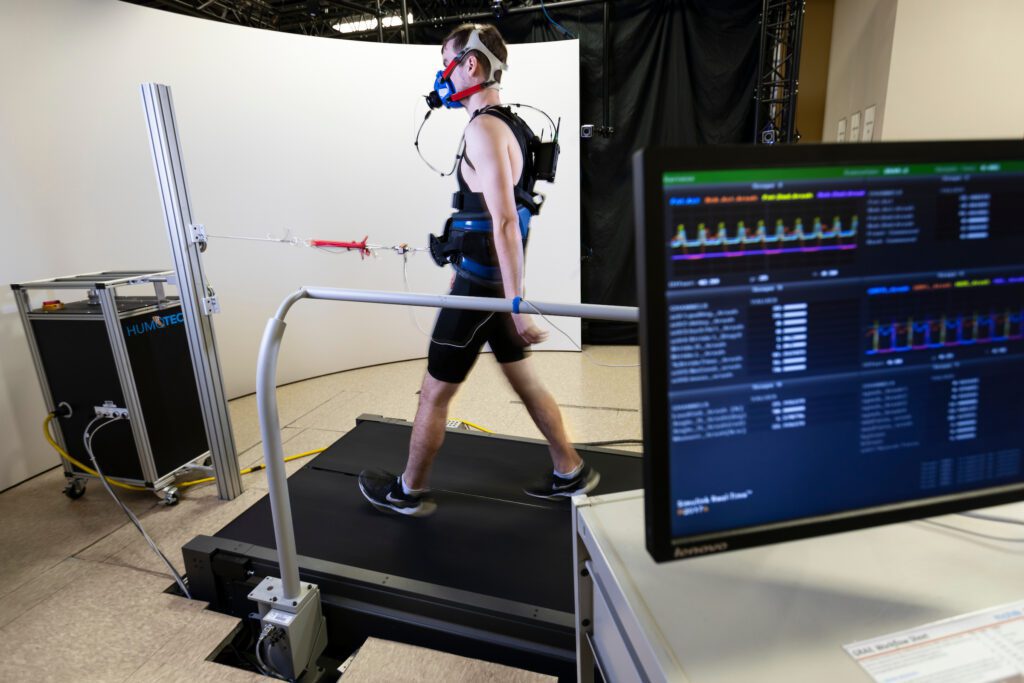 Alex Pzewaltowski walks on a treadmill as a motor pulls on his center of mass in a gait lab at the University of Nebraska Omaha’s Biomechanics Building