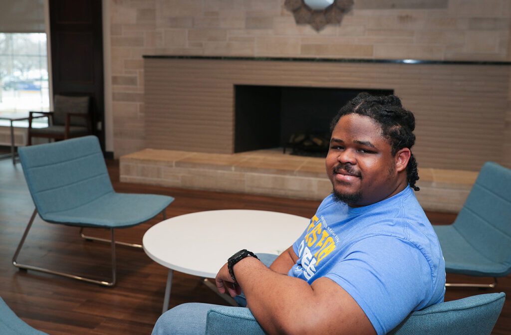 UNK Student posing in front of fireplace on campus