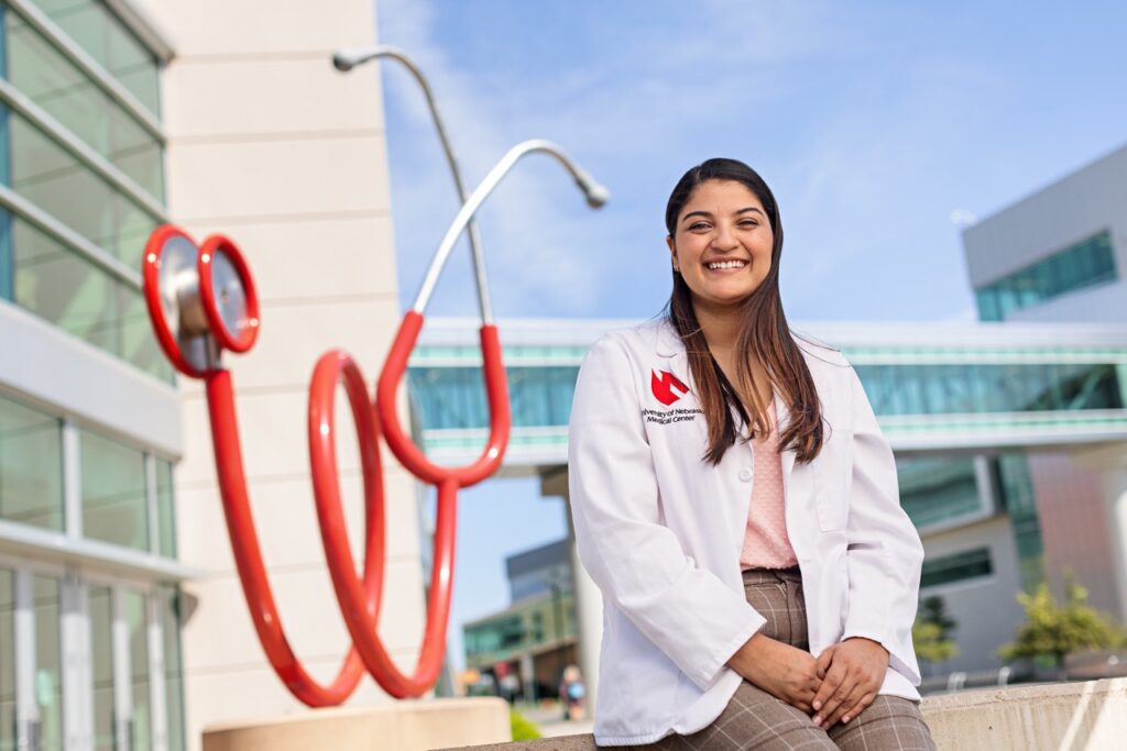 Daniela Cortes Reyes poses in front of stethoscope statue at UNMC