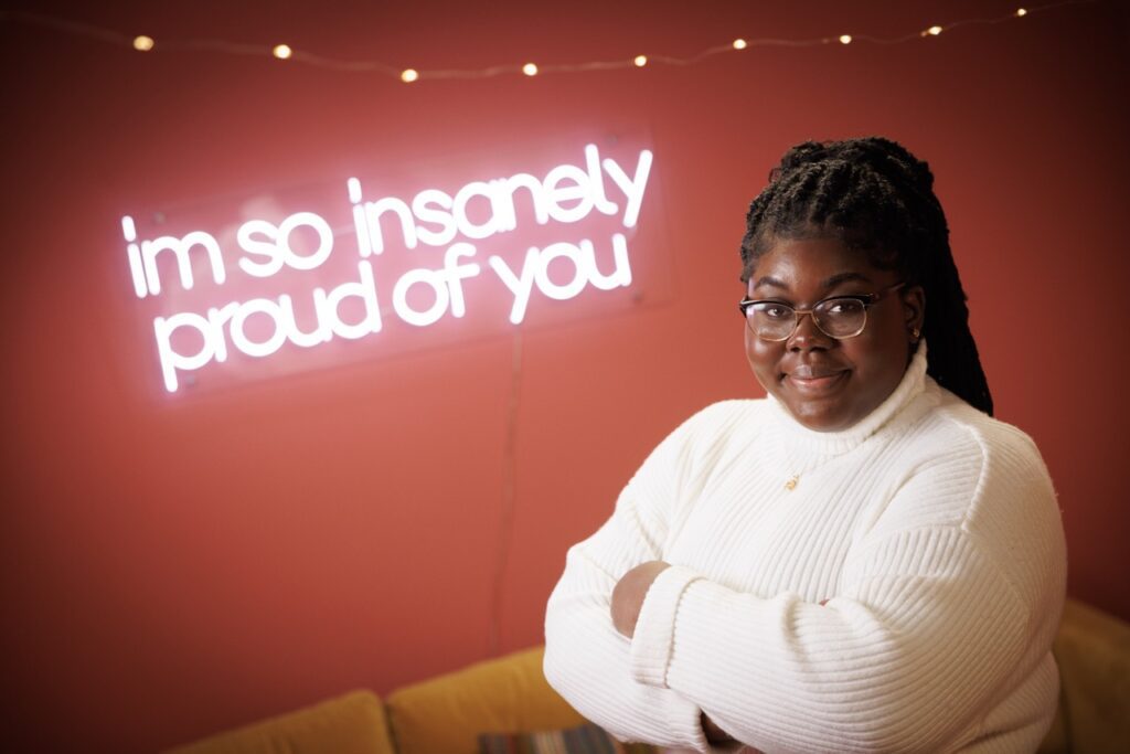 Odelia Amenyah poses in front of sign reading "im so insanely proud of you"