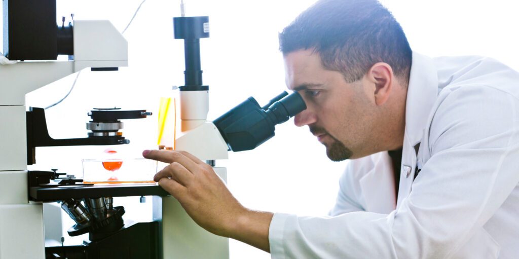 Researcher looking into microscope in a lab